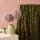 Die Ansicht zeigt den Viscosestoff Java ivy green weich fliessend über eine Stange gehaengt, welche an der Wand befestigt ist. Es ist ein Stoffdruck mit blauen und lila Punkten, rosa und pertrolfarbenen Strichen auf avocadogruenen Untergrund.