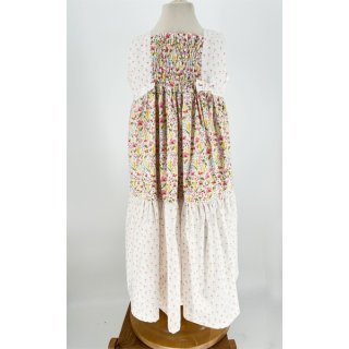Das Bild zeigt das Sommerkleid Sunny Day, Es hat eine lange Rockform, die weit schwingt. Das Vorderteil besticht durch seinen gesmokten Bereich. Dieser ist mit 2 kleinen Schleifen benaeht. Dir Grundfarbe des Kleides ist weiss und mit roten, pinken und gelben Blumen, die einer Blumenwiese aehneln, bedruckt.