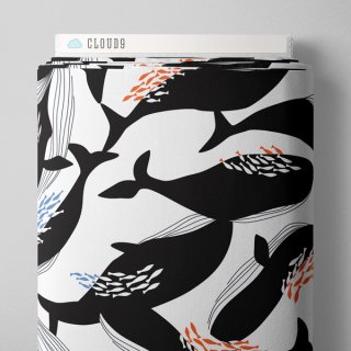 Die Ansicht zeigt den oberen Ausschnitt des Stoffballens des Canvasstoffes Happy Whales. Es sind schwarze Bartenwale auf weissem Untergrund gedruckt. Um sie herum schwimmen kleine Fischschwaerme in rot, blau und weiss. 