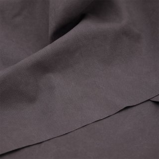 Das Bild zeigt den Stoff  Heavy Washed Canvas in calm Grey. Es ist ein dunkles grau. Dieser Stoff liegt leicht eingefaltet auf einem Tisch.