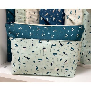 Das Bild zeigt das Krimskramstaeschchen Sands Of Time. Es ist die Front des DIN A5 großen Täschchen abgebildet. Der Hauptstoff ist ein dunkelblauer Baumwollstoff mit kleinen tuerkis und beigefarbenen angedeuteten Blueten. Aussenvor ist in tuerkis ein Baumwollstoff fuer zwei Aussenfaecher. Auf ihm sind blaue und weisse Leuchtuerme, Segelboote, Moewen und Wale gedruckt.