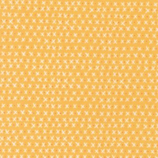Das Bild zeigt einen gelben Baumwollstoff  mit kleinen beigen bzw. weissen x und mini roten oder orangfarbenen Puenktchen.