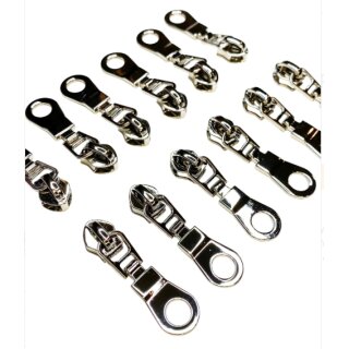 Das Bild zeigt zwoelf nickelfarbene Zipper zu 6 Stueck in zwei Reihen liegend auf einem weissen Untergrund.